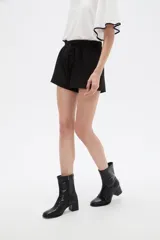 Short negro de poliéster, con pinzas, corte recto y tiro alto, con lazo ajustable en la cintura.
