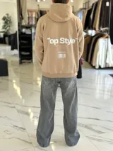 Canguro negro oversize con capucha y gran estampado blanco en la espalda con el texto "Top Style", "Dream big. Work hard. Make it real.", "SINCE 2021" y un código de barras.