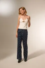 Musculosa de color blanco con breteles finos, escote en V y detalle de aberturas frontales con lazos decorativos.