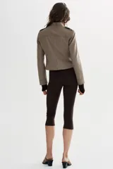 Blazer entallada color beige con rayas verticales finas, cuello redondo y manga larga. Presenta trabillas en los hombros y botones metálicos decorativos en el frente. Cierre frontal con cremallera y forro interior.