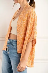 Kimono oversize color naranja con estampado floral blanco, mangas 3/4 y confeccionado en rayón.