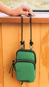 Bolso porta celular con cierre frontal, compartimentos internos para tarjetas y bolsillo trasero. Incluye correa elástica regulable y desmontable.