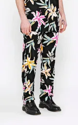 Pantalón recto de calce regular, color negro, con estampado de flores tropicales en tonos blanco, amarillo, rosado y celeste.