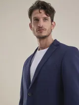 Blazer formal color negro, confeccionado en tela texturada, con solapas clásicas, cierre de dos botones frontales y bolsillos con solapa.