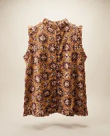 Blusa sin mangas de algodón con estampado de inspiración vintage, cuello alto con volados, detalles de volados fruncidos en las sisas y en el ruedo, y cierre posterior con botones forrados en la misma tela.