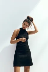 Vestido mini negro de punto arrugado, con escote halter y cuello elevado.