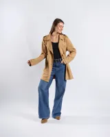 Campera tipo trench de color habano, de corte a la cadera, confeccionada en material textil símil gamuza. Presenta solapa cruzada, doble botonadura frontal, hombreras y cinturón ajustable para anudar en la cintura. Incluye bolsillos delanteros y puños con trabilla.