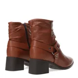 Botas de cuero color suela, con caña media arrugada y detalle de correa con hebilla metálica en el tobillo. Posee taco cuadrado y punta redondeada.