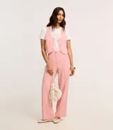 Remera de algodón blanca con cuello redondo y mangas cortas. Presenta una estampa frontal con la frase 'Too glam to give a damn' decorada con strass rosados y detalles de pliegues en los hombros.