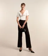 Blusa de manga corta confeccionada en tejido de viscosa texturizado, con escote en V profundo que presenta un detalle de aro metálico central.