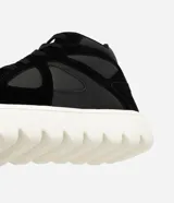 Championes de corte medio confeccionados en poliuretano negro, con diseño de paneles combinados y perforaciones laterales. Presentan cierre con cordones y una suela track alta de color blanco con relieve.