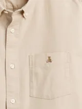 Camisa de corte clásico confeccionada en tejido Oxford, color verde oliva. Presenta cuello abotonado, cierre frontal con botones, mangas largas con puños abotonados y un bolsillo en el pecho con el logo del oso Brannan bordado.