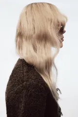 Chaqueta de punto de textura bouclé en color marrón oscuro, con cuello redondo y manga larga. Presenta detalles de vivo a contraste en color crema en los bordes y cierre frontal mediante lazadas decorativas con flecos.