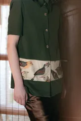 Camisa verde militar de manga corta con botones nacarados y corte estampado en el delantero con diseño de aves.