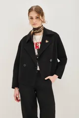 Tapado corto de paño negro, con diseño de doble botonadura, cuello solapa y mangas tres cuartos.