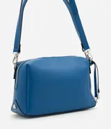 Bolso tipo shoulder de diseño rectangular estructurado en color azul. Cuenta con cierre metálico superior, herrajes plateados y correa larga ajustable y removible.