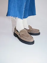 Mocasines Mutma Gales de cuero color tostado, con plataforma gruesa dentada, detalles de tachas metálicas, argollas y tira lateral con hebilla.