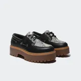 Zapatos tipo náutico Timberland con plataforma dentada color marrón. El cuerpo es de cuero negro con detalles de ojalillos metálicos y un panel superior con estampado animal print texturizado.