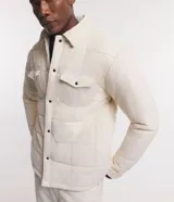 Campera puffer de terciopelo cotele color crema, con cuello inglés, manga larga, abotonado delantero y bolsillos de solapa en el pecho.