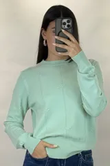 Buzo de hilo color verde menta, de cuello redondo y manga larga, con diseño de líneas verticales en relieve y pequeños detalles bordados.