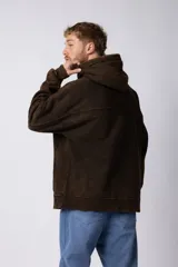 Buzo canguro de frisa gruesa con capucha, diseño oversize y acabado con efecto gastado. Presenta recortes horizontales en el frente y puños con elástico.