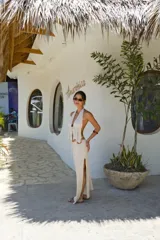 Falda larga tejida color marrón con brillo metálico, corte al cuerpo, abertura alta en la pierna y recortes laterales con cordones ajustables.