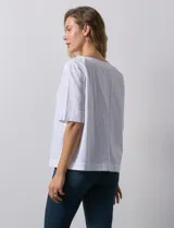 Blusa blanca de algodón, manga corta amplia, con escote redondo y detalle de botones en los tajos laterales del ruedo.