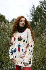 Buzo tejido de lana merino color crema, con diseño bordado a mano que representa escenas de granja, incluyendo figuras de granjeros, casas, tractores y animales. Presenta un corte holgado y cuello redondo.