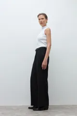 Pantalón de corte sastrero y pierna ancha, confeccionado en lyocell. Presenta pinzas en la cintura, cierre frontal con botón y bolsillos laterales. Incluye un cinturón fino de cuero con hebilla metálica.