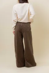 Pantalón de denim color marrón, de tiro medio-alto y calce wide leg con pierna amplia.