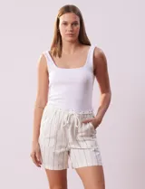 Short color crema con finas rayas verticales grises, pretina elastizada con cordón de ajuste, bolsillos delanteros y traseros.