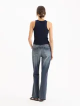 Jeans Fred de tiro alto y corte recto, con diseño ligeramente acampanado hacia el dobladillo, lavado azul medio con efecto desgastado y detalles deshilachados en los tobillos.