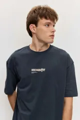 Remera de corte oversize color blanco tiza, de manga corta y cuello redondo, con pequeño estampado gráfico azul en el pecho.