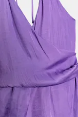 Top de satén color lila con escote en pico cruzado, tirantes finos ajustables y bajo asimétrico con caída lateral.