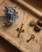 Collar con dije de cruz de bronce con baño de oro y piedras ovaladas color azul.