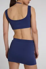 Top deportivo azul con doble escote superpuesto y cintura con elásticos. Confeccionado con textil Activelu con protección UV50+ y nula transparencia.