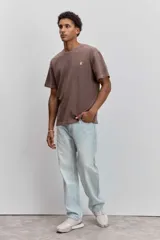 Remera de algodón color marrón con efecto lavado, de corte clásico y cuello redondo. Presenta un pequeño bordado de un pájaro en el pecho.