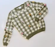 Sweater tejido en jacquard de cuadros bicolor verde y crudo, elaborado en lana merino, con delicados bordados florales hechos a mano.