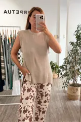 Chaleco tejido de punto color visón, con cuello redondo, hombreras marcadas y tajos laterales en el ruedo.