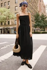 Vestido midi negro de escote recto con tirantes finos ajustables, espalda descubierta y falda amplia con bajo de bordados perforados a tono y detalle de puntilla.
