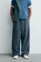Pantalón de corte ancho (baggy fit) color azul marino con estampado de cuadros pequeños en tonos azul claro y marrón. Presenta cintura elástica ajustable con cordón interior y bolsillos frontales.