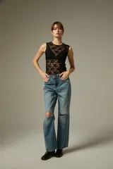 Pantalon de jean azul con corte recto y ancho, presenta aberturas en las rodillas y detalles de tachas metálicas a lo largo de las costuras laterales.