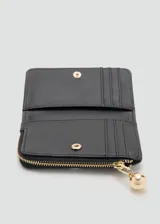 Billetera pequeña de poliuretano efecto piel en color negro, con cierre de solapa con botón a presión, seis ranuras para tarjetas y bolsillo lateral con cierre de cremallera. Incluye detalles metálicos dorados y el logo de la marca estampado en el frente.