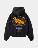 Canguro con capucha de corte regular, color negro con efecto lavado. Presenta un diseño gráfico estampado en la espalda en color naranja que incluye ilustraciones de carpinchos sobre una cuadrícula de globo terráqueo y texto descriptivo.