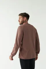 Remera de hombre negra de manga larga con puños, escote redondo y bolsillo en el pecho con etiqueta de marca.