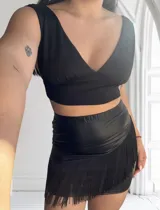 Minifalda negra de cuero sintético con flecos en el ruedo.