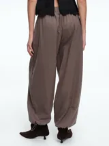 Pantalón de silueta holgada y cómoda, color gris, con cintura elástica y bajo ajustable mediante cordón. Cuenta con bolsillos laterales ocultos y diseño de estilo babucha.
