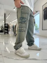 Pantalón cargo de jean azul claro, con bolsillos laterales tipo cargo en las piernas y bolsillos frontales aplicados, de corte ancho y holgado.