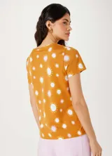 Remera color naranja con estampado de soles blancos y rosados.