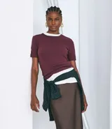 Blusa de manga corta confeccionada en algodón pima, con cuello redondo y diseño liso. Presenta un corte clásico con el bajo ligeramente más largo en la parte posterior.